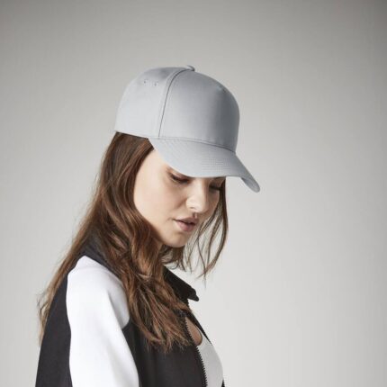 Leichte graue 5-Panel-Cap mit Druck, getragen von einer Frau mit braunen Haaren, Blick nach unten gerichtet.