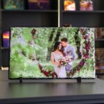 Schiefertafel mit Fotodruck eines Brautpaars im Wald, eingerahmt von einem Herz aus roten Blumen.