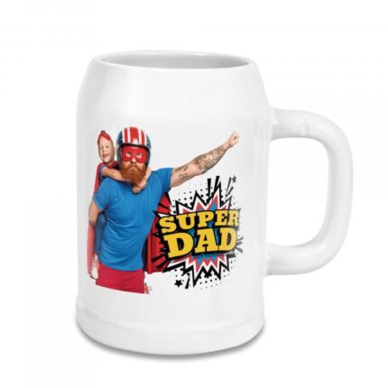 Weißer Bierkrug mit buntem Comic-Druck „Super Dad“ und einem Vater in Superhelden-Kostüm, der sein Kind auf dem Rücken trägt.