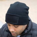 Schwarze Double Knit Thinsulate™ Mütze mit Logopatch, getragen von einem Mann im Winteroutfit.