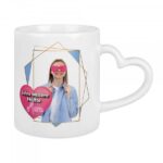 Weiße Sublitasse mit herzförmigem Henkel und individuellem Druck eines Porträts mit rosafarbenen Herz-Augen sowie dem Text „Seine bessere Hälfte – Mara“.