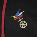 Embroidered Fastnacht emblem on black hoodie with jester hats and Mainz city wheel in red, yellow, and blue thread.