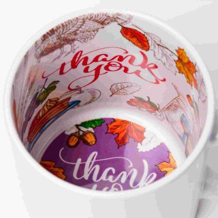 Herbstlich gestaltete Innenseite einer Tasse mit dem Schriftzug „Thank You“, umgeben von bunten Blättern, Eicheln, Gemüse und einem Truthahn.