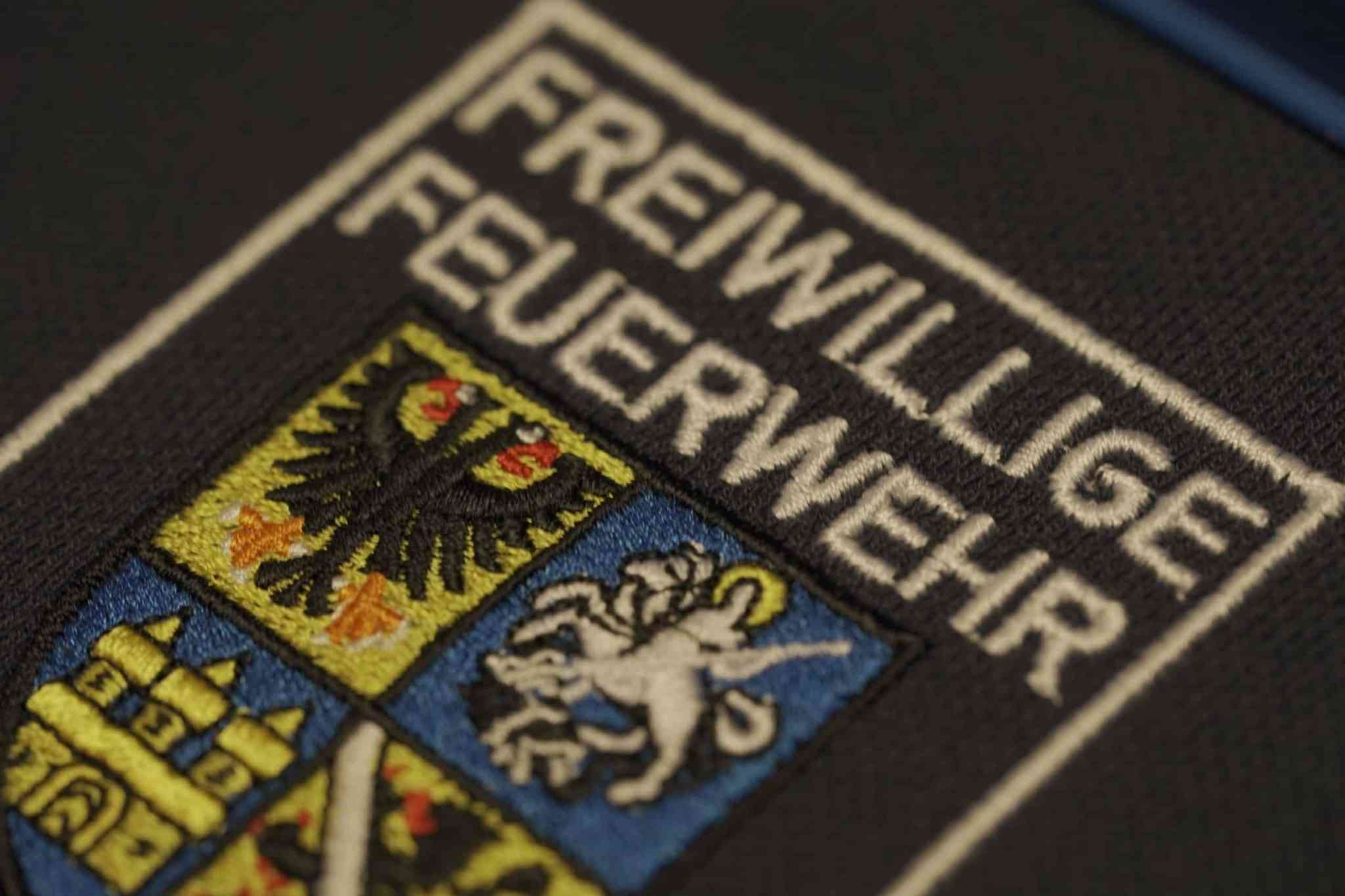 Gesticktes Abzeichen mit Wappen der Freiwilligen Feuerwehr auf dunklem Stoff