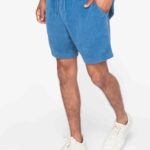 Umweltfreundliche Herrenshorts aus Frottee in Blau, getragen von einem Modell mit weißen Sneakers